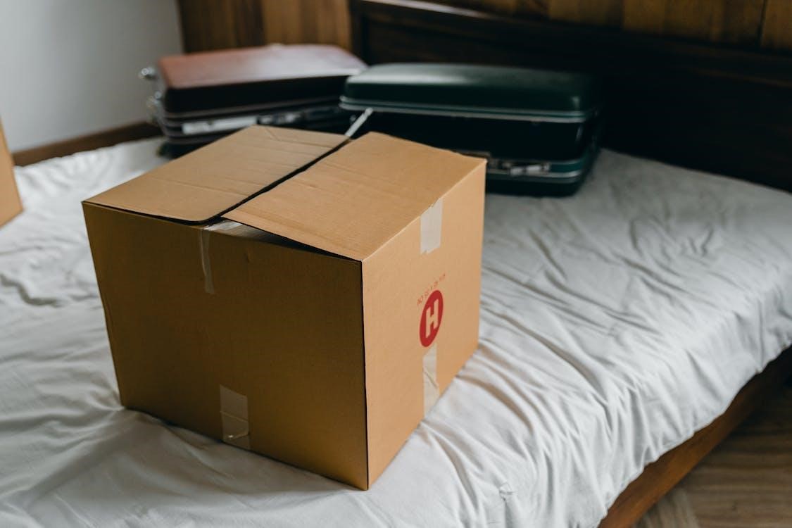 Free Carton box and suitcases for relocation on bed Stock Photo
